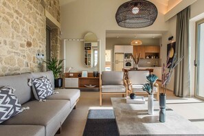 A modern living room with a stone wall, a sofa, a coffee table, and a kitchen in the background.
