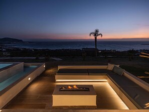 A poolside area with a fire pit and lounge seating overlooking the ocean at dusk. - Villa Cielo I Free Heated Pool Stunning Seaview (Kissamos)