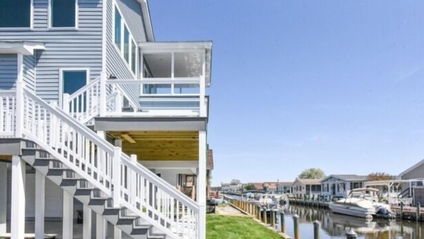 Une maison à deux étages avec une terrasse en bois et un escalier menant à un balcon.