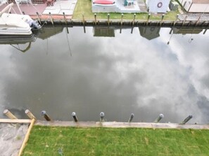 A calm water body with a grassy bank and a wooden dock. - Seas The Day says it all. 4 BR house on the canal! (Selbyville)