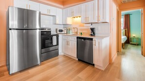 A modern kitchen with stainless steel appliances, white cabinetry, and a wooden floor.