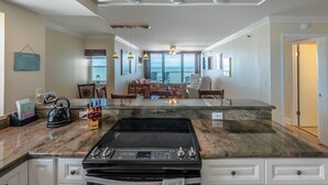 Een ruime keuken met een groot eiland, een eethoek met stoelen en uitzicht op de oceaan.