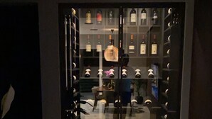 A hotel entrance with a glass door, a seating area with tables and chairs, and a wine rack with bottles. - Apartment 20 meters from the sea luxurious modern with all amenities (Tas-Sliema)