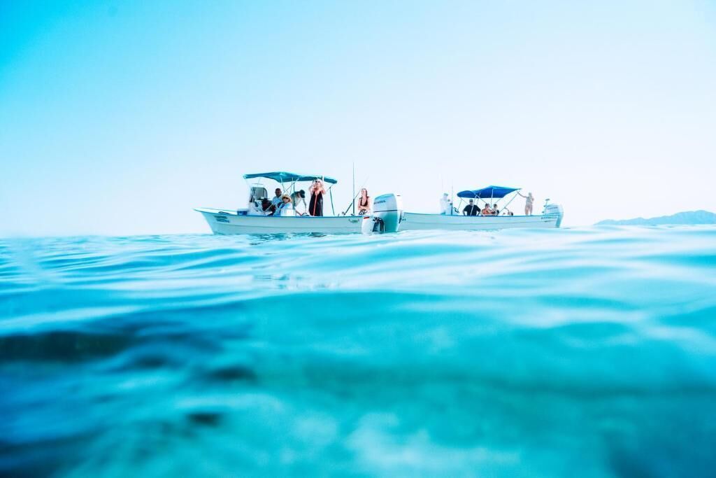 Deux bateaux sur une eau calme, avec des personnes à bord.