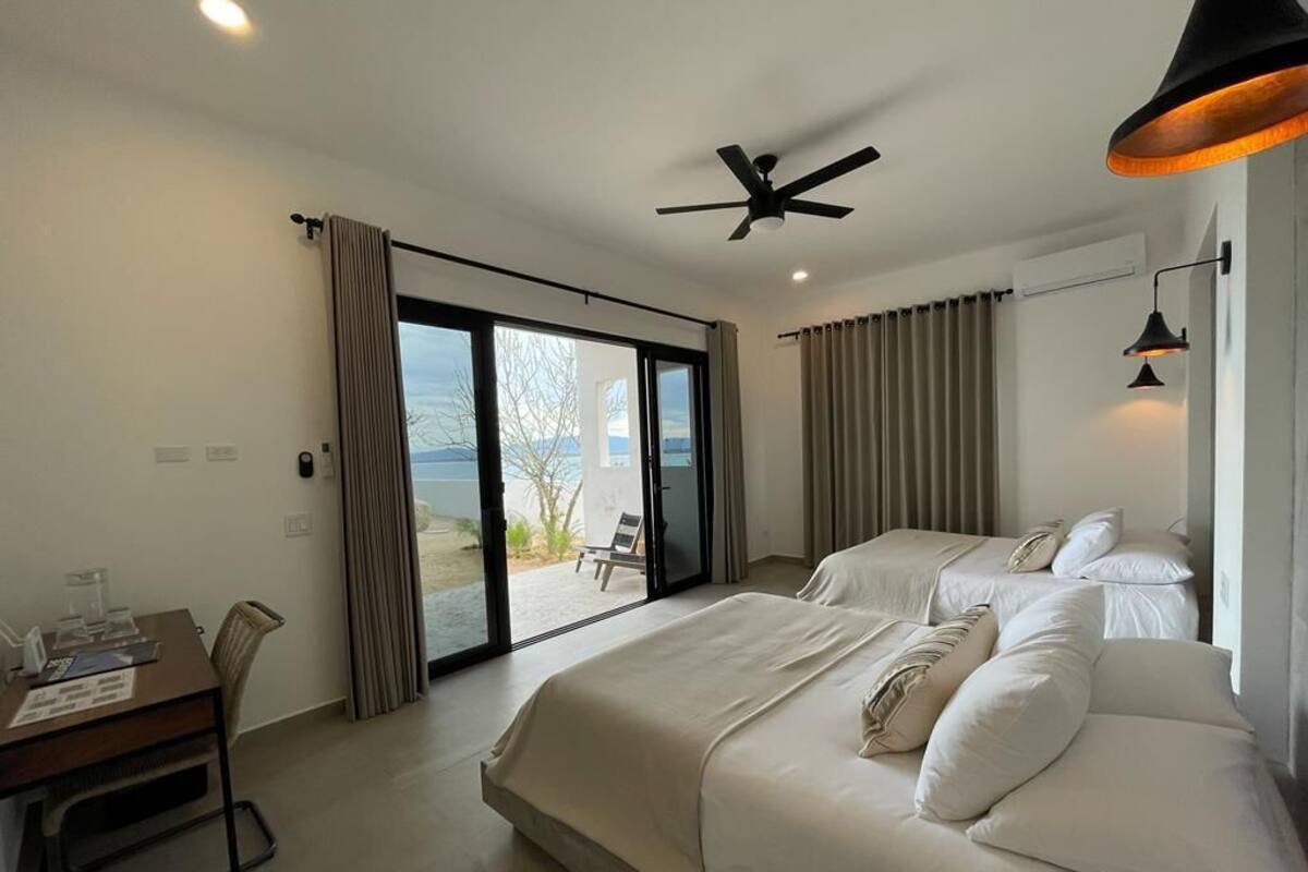 Ein Hotelzimmer mit zwei Betten, einem Schreibtisch und Meerblick.