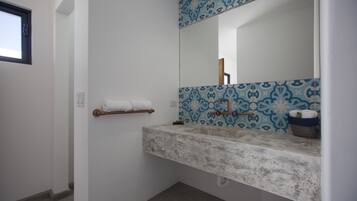 A bathroom with a white sink, blue patterned tiles, a towel rack, and a mirror.