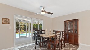 A dining area with a table and chairs, a ceiling fan, and a cabinet. - Mermaid Shack with pool 5 min to beach,venues,restaurants (Jupiter)