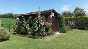 Ein rustikales Haus mit Garten, umgeben von einem Zaun und einem Feld.