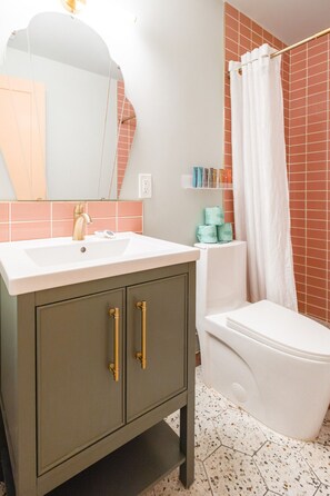 A bathroom with a white sink, a mirror, a toilet, and a shower curtain.