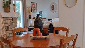 A dining area with a wooden table and chairs, a chandelier, and a view into the living room.