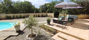 Relax by the pool in a serene patio area with a shaded seating arrangement and lush greenery.