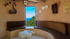 A cozy room with a curved sofa, a small round table, and a view of the sea through a large window. - Villa Las Tres Yucas (Sant Antoni de Portmany)