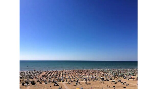 Ein überfüllter Strand mit vielen Sonnenschirmen und Badegästen.