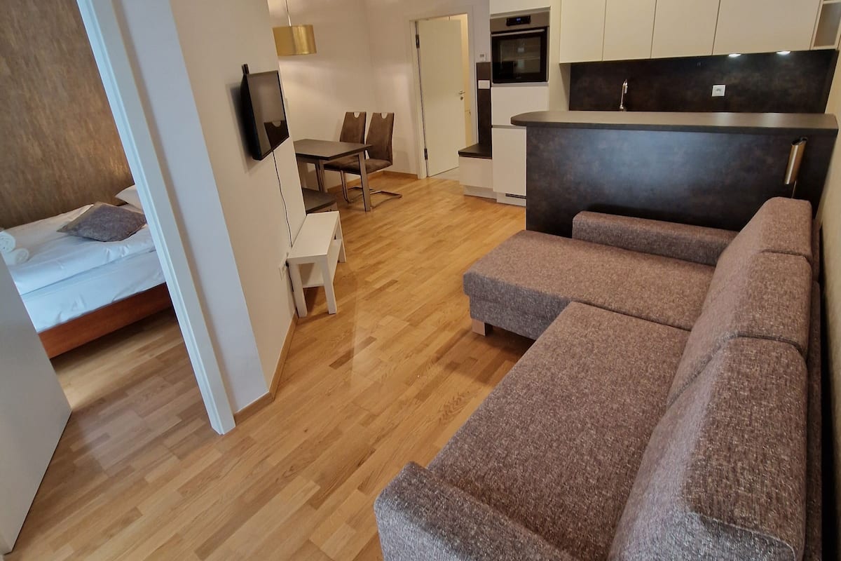 A modern living space with a sofa, a dining area, and a kitchenette.