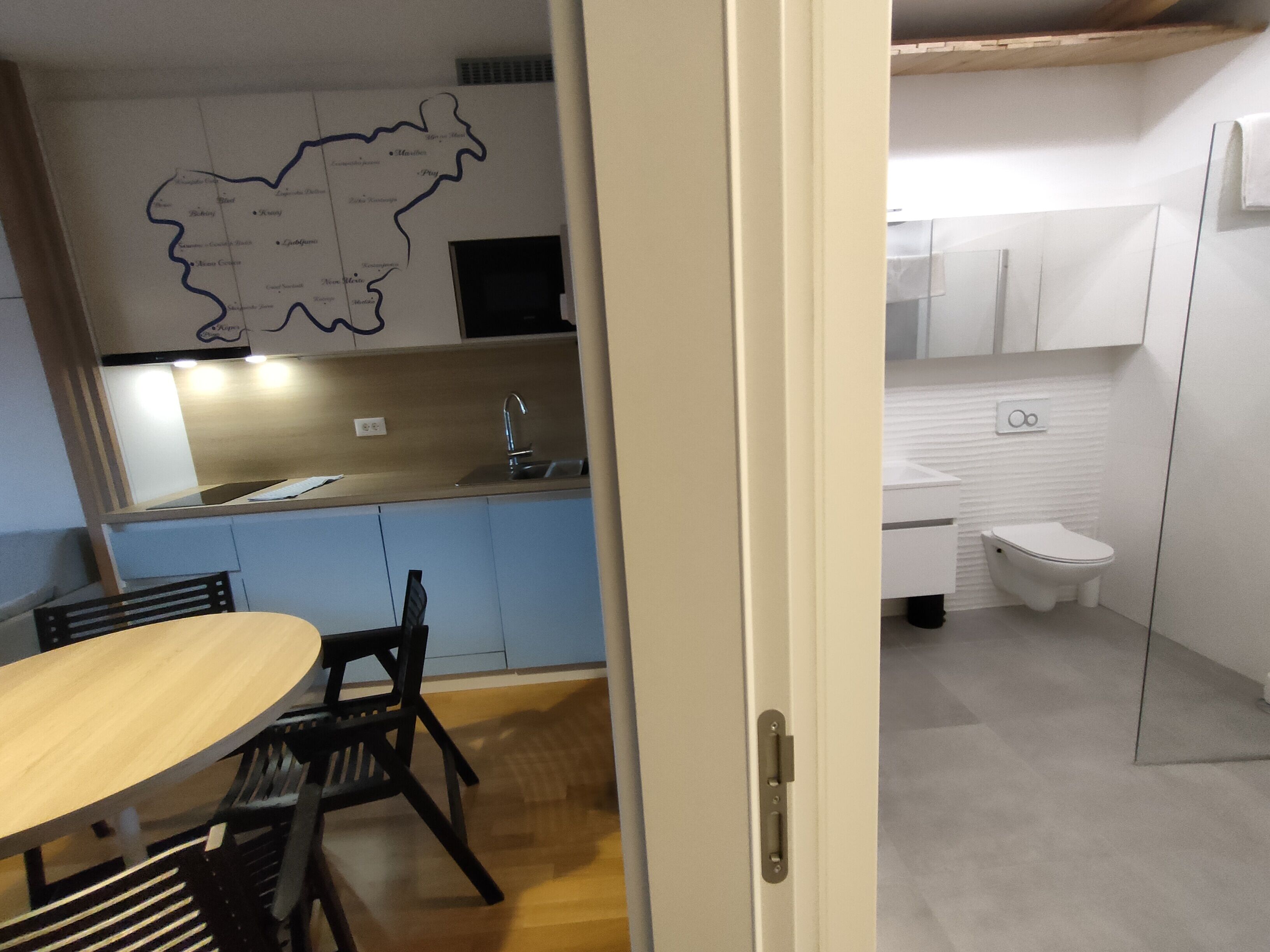 Een kleine keuken met een eethoek, een kaart aan de muur en een kleine badkamer.