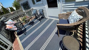 A covered patio with outdoor furniture, a striped floor, and a house with a number '431' on the window. - Beach Haven Long Beach Island (Beach Haven)