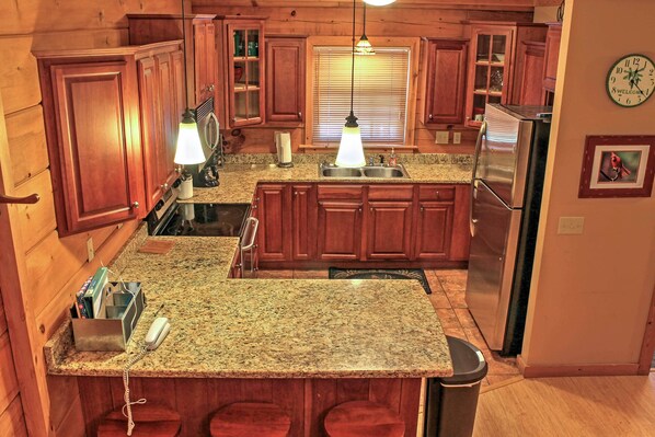 A kitchen with wooden cabinets, granite countertops, a stainless steel refrigerator, and a clock on the wall. - Ski-In/Ski Out Townhome w/ Beautiful View w/Hot Tub. (Snowshoe)