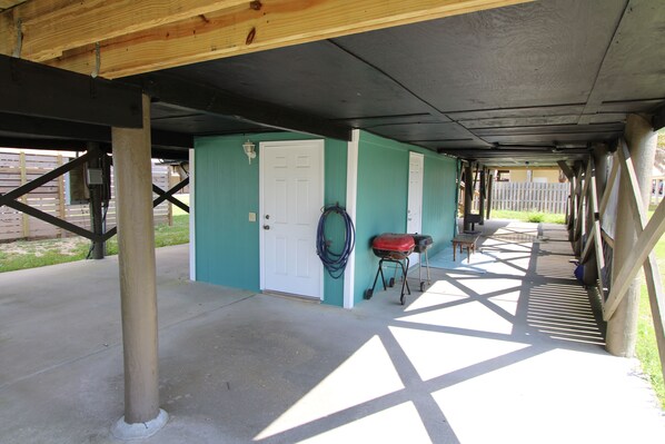 A covered outdoor area with a concrete floor, a door, a hose reel, and a grill. - 🐕PET FRIENDLY🐕…🌊Paradise is calling, Pick up! (Gulf Shores)