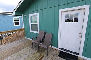 A wooden deck with two wicker chairs and a white door with a window. - 🐕PET FRIENDLY🐕…🌊Paradise is calling, Pick up! (Gulf Shores)