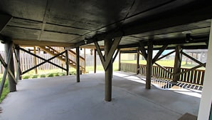 Een overdekt terras buiten, met betonnen vloer en houten leuningen.