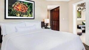 Een hotelkamer met een groot bed, een kledingkast, een bureau en een ingelijste foto aan de muur.