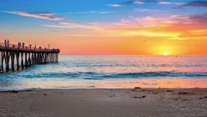 Eine Pier, die sich in ruhiges Wasser bis zum Sonnenuntergang erstreckt.