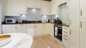 A modern kitchen with white cabinets, a marble countertop, a microwave, a toaster, and an oven.