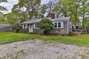 A single-story house with a front porch, a chimney, and a small front yard with a gravel area and a tree.