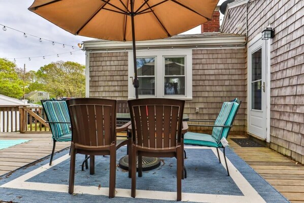 Eine Terrasse mit Tisch, Stühlen und Sonnenschirm, sowie ein Holzdeck.