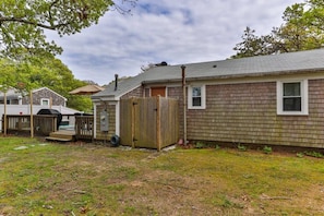 Ein eingeschossiges Haus mit einem umzäunten Garten, einer Holzterrasse und einer Garage.