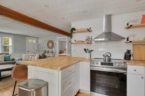 A modern kitchen with white cabinetry, a wooden countertop, a stainless steel range hood, and an oven. - Perfect House In Yarmouth, Book Now & Come Relax! (Yarmouth)
