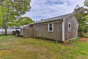 Une maison de plain-pied avec un toit en pente, une cour arrière clôturée et une terrasse en bois.