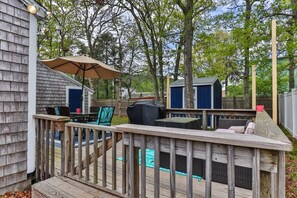 A wooden deck with outdoor furniture, a grill, and a pool.