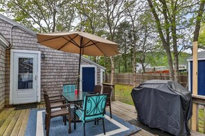 Un jardin avec une terrasse, un barbecue couvert et un espace repas comprenant des chaises et une table.
