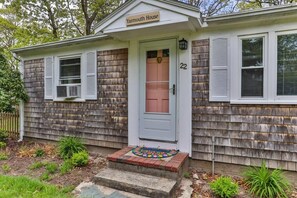 A single-story house with a white door, a small porch with steps, and a number '22' on the wall.