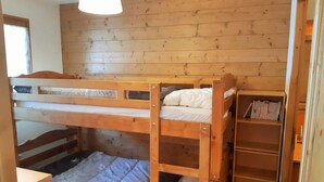Dormitorio con literas, paredes de madera y estantería.