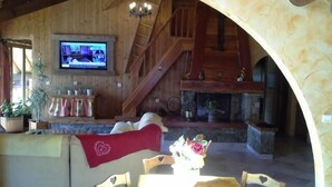 A cozy living area with a wooden interior, a fireplace, a television, and a dining table with chairs. - 3rd floor, balcony, ski locker, 145m², Valloire (Valloire)