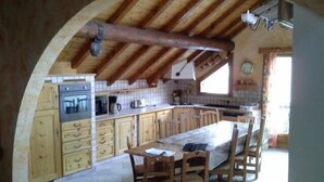 A rustic kitchen with wooden cabinets, a large island, and a dining area with wooden chairs. - 3rd floor, balcony, ski locker, 145m², Valloire (Valloire)