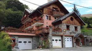 A chalet-style building with a stone facade, wooden balconies, and a garage. - 3rd floor, balcony, ski locker, 145m², Valloire (Valloire)