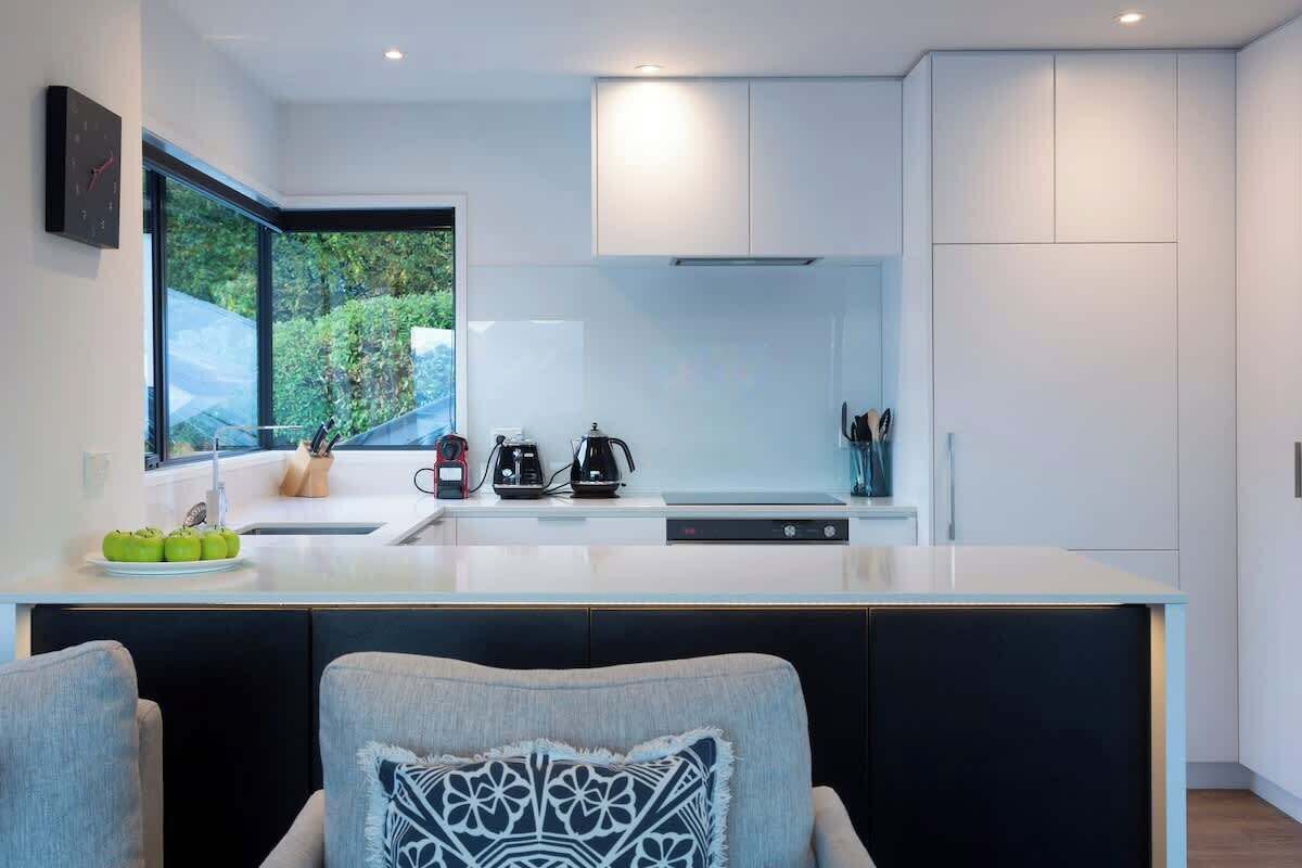 A modern kitchen with a large window, white cabinetry, and a central island with appliances.
