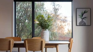 A dining area with a table and chairs, a vase with flowers, and a framed picture on the wall. - Villa Awa | Lake Views,BBQ,Fireplace, Free Parking (Queenstown)