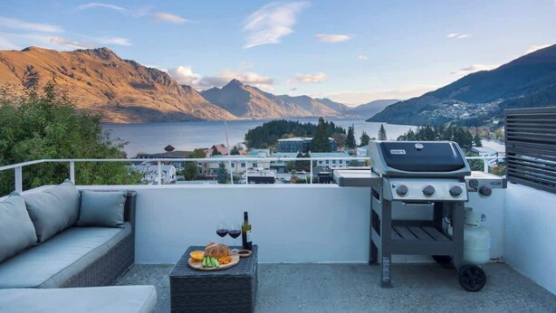 A rooftop terrace with a grill, seating area, and a scenic view of mountains and a lake. - Villa Awa | Lake Views,BBQ,Fireplace, Free Parking (Queenstown)