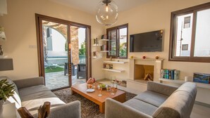 Una sala de estar moderna con chimenea, un televisor de pantalla plana y un ventanal con vistas a un jardín.