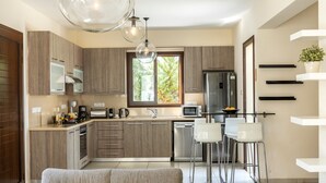 Una cocina moderna con armarios de madera, electrodomésticos de acero inoxidable y una barra con taburetes blancos.