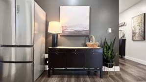 Una cocina moderna con un refrigerador de acero inoxidable, un armario de madera oscura y una lámpara fijada a la pared.