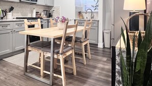 Una cocina moderna con armarios grises, una mesa de comedor de madera con cuatro sillas, un microondas y un fregadero.