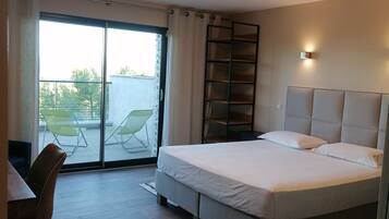 Quarto de hotel moderno com uma cama grande, uma escrivaninha e vista para o exterior.