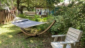 A hammock and a wooden bench in a garden setting. - OBX gem, private studio, couple's nest!  (Kill Devil Hills)