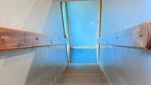 A wooden staircase with a blue carpet leading to a door. - OBX gem, private studio, couple's nest!  (Kill Devil Hills)