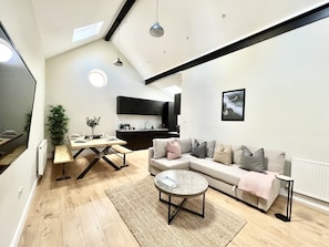 A modern living room with a sofa, coffee table, and dining area.